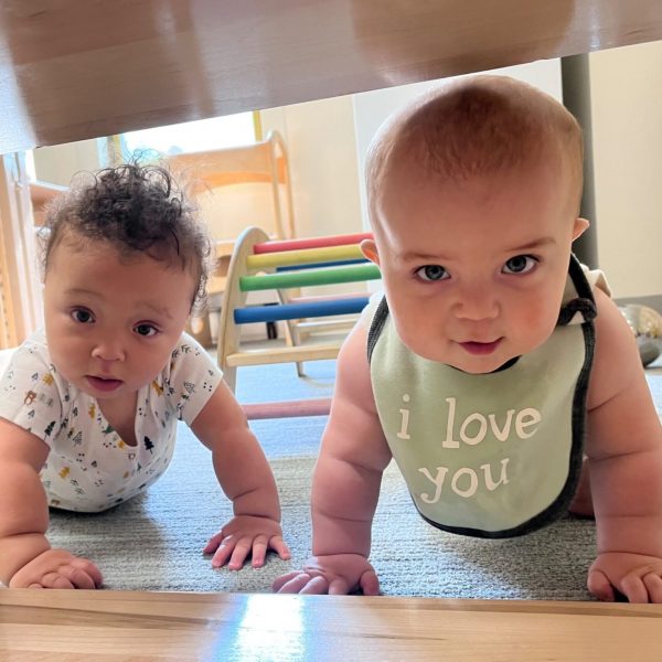 Two happy infants crawl towards the camera.